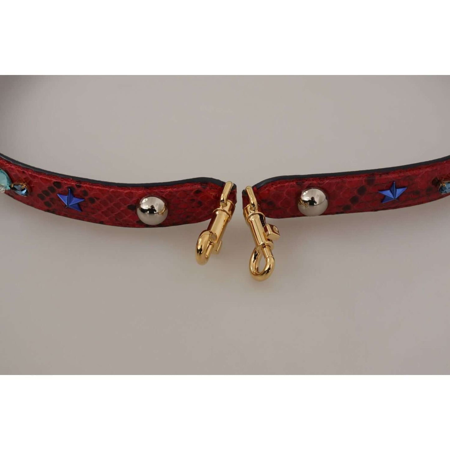 Dolce & Gabbana red python leather shoulder strap with gold-tone lobster clasps, adorned with blue stars and silver accents.
