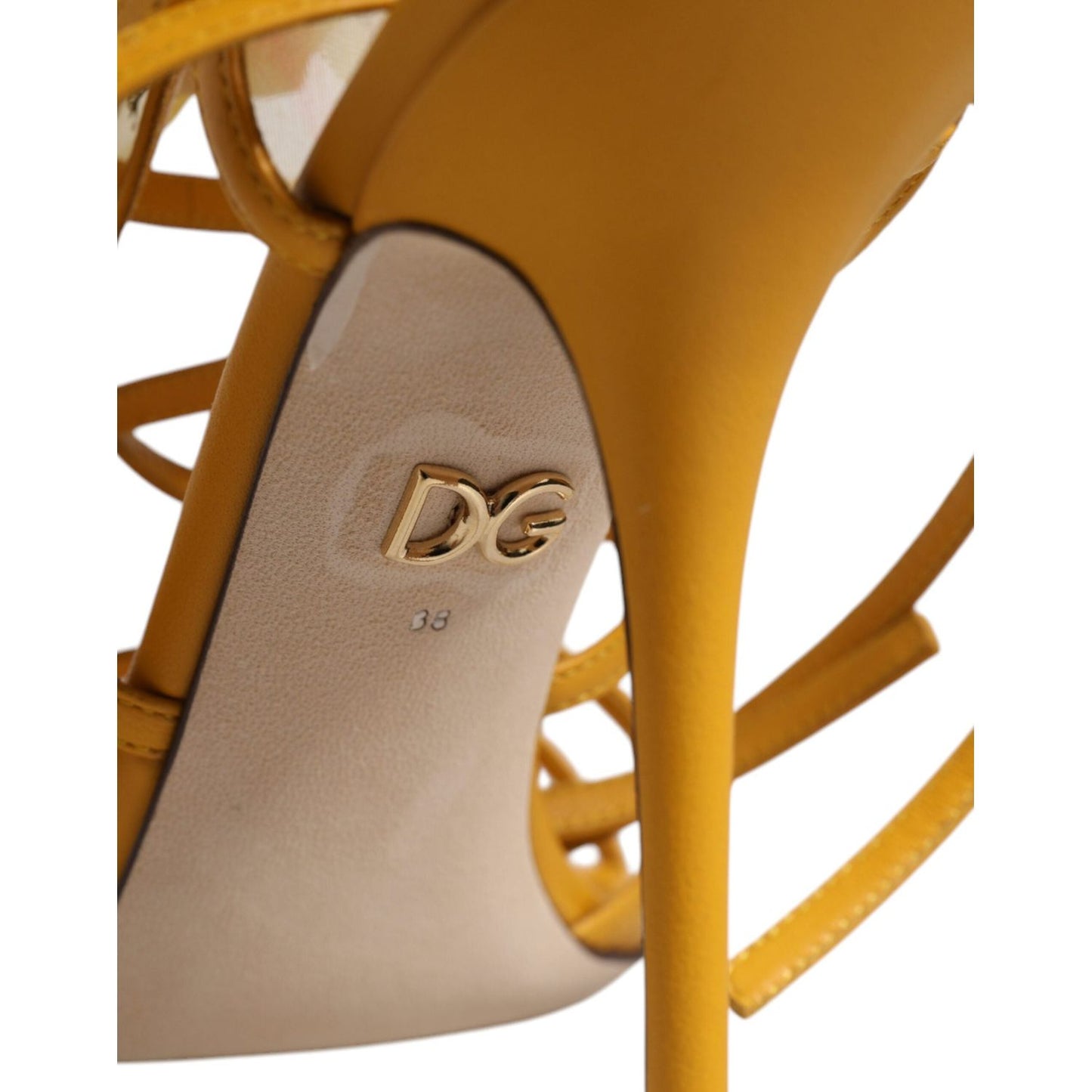 Close-up of Dolce & Gabbana yellow stiletto heel with floral embellishments and DG logo, showing leather sole detail. Made in Italy.