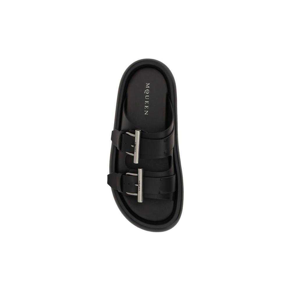 Alexander McQueen black leather sandals with double straps and metal buckles, featuring logo-embossed convex sole for modern style.