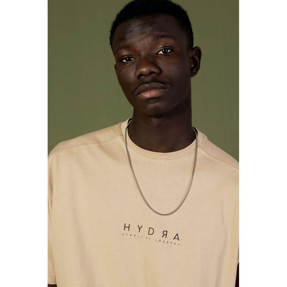 Model wearing Hydra Clothing beige cotton sweatsuit for men, spring/summer collection, featuring a minimalist design.