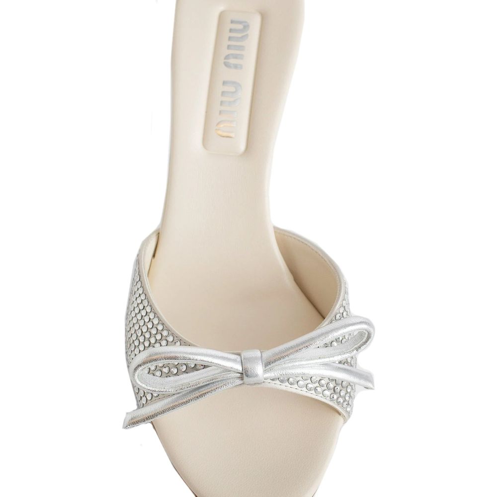 Miu Miu Silver Silk Mules with crystal embellishments, open toe, top bow detail, and branded insole. Elegant slip-on design.