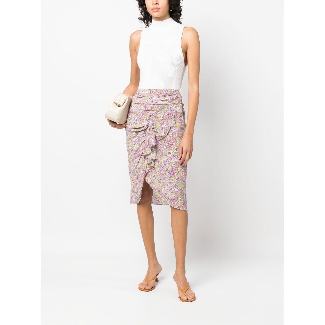 Model wearing a beige Iro knee-length graphic-print skirt with draped and ruched detailing, styled with a white top and beige accessories.