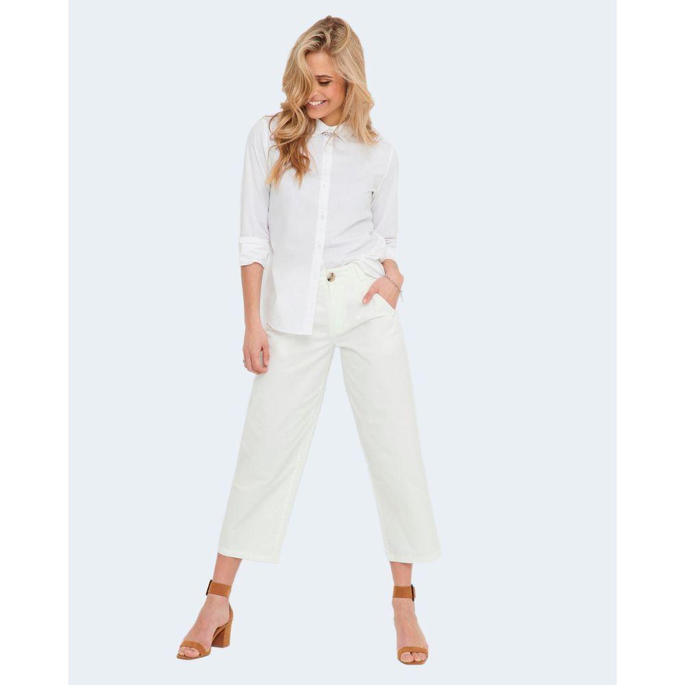 Woman wearing Jacqueline De Yong white cotton shirt with long sleeves, paired with white pants and heels, showing versatile style.