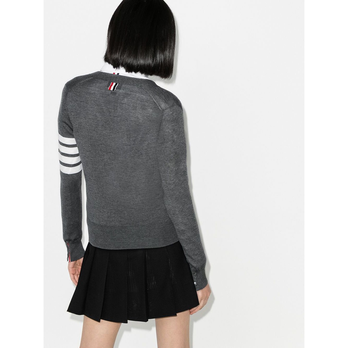 Back view of a model wearing Thom Browne Sweaters Grey, featuring a grey wool cardigan with 4Bar stripes, long sleeves, and ribbed cuffs.
