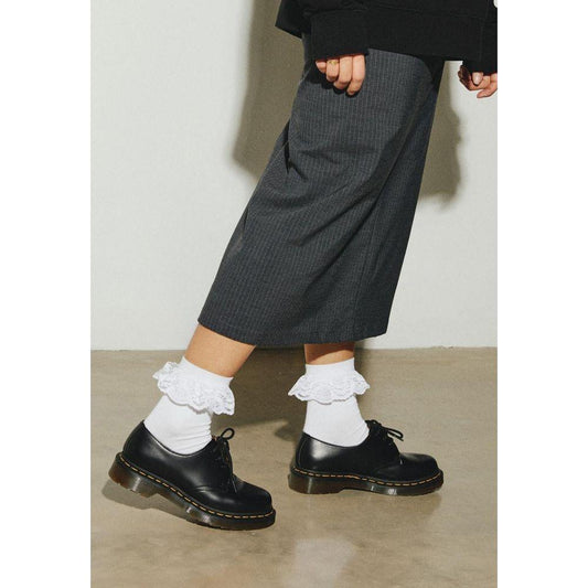 Woman wearing Dr. Martens white polyester tights and socks, showcasing fall/winter collection with lace trim detail.