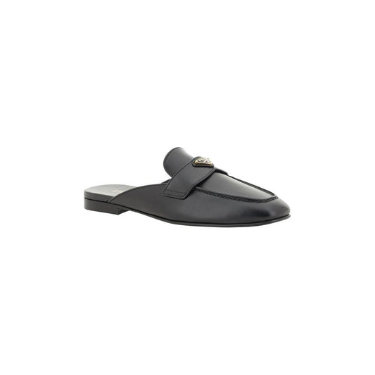 Black leather Prada mules with round toe, triangular plaque, flat sole, and logo insole.
