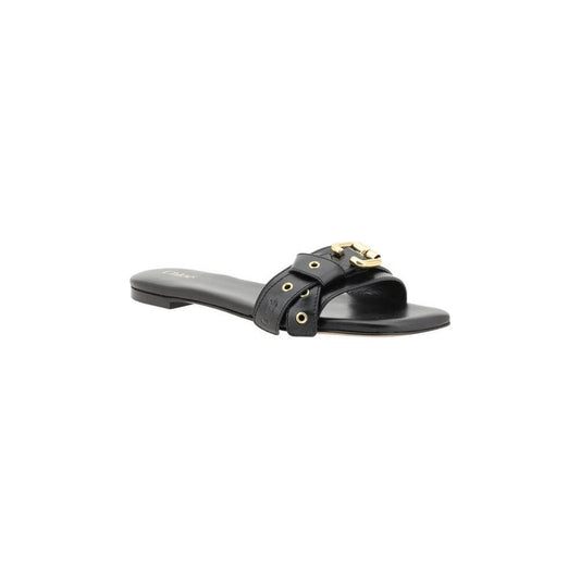 Chloé Mae Sandals in black leather with knotted straps, gold eyelets, and signature Paddington buckle on flat sole.
