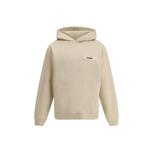 Jacquemus cotton hoodie with plush interior and logo patch, featuring ribbed cuffs and hem for a snug fit, neutral color.