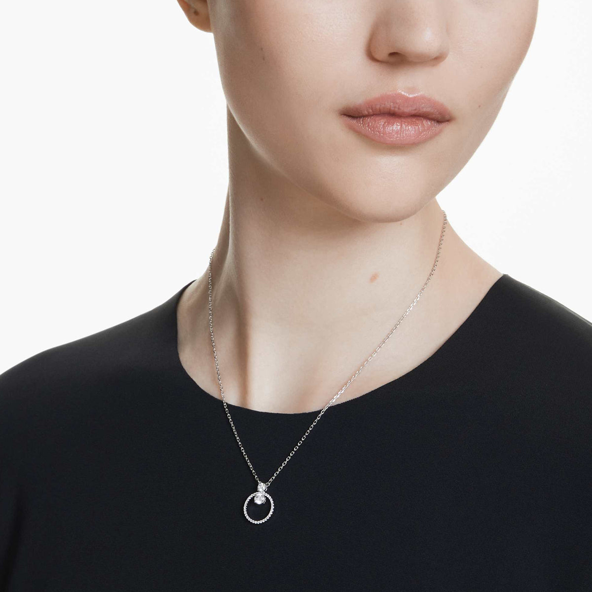 Woman wearing SWAROVSKI Mod. 5692261 silver necklace with circular pendant displayed in official box.