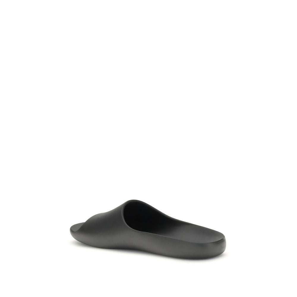 The Row Black Rubber Slippers with contoured footbed, featuring minimalist design and seamless construction, ideal for understated style.