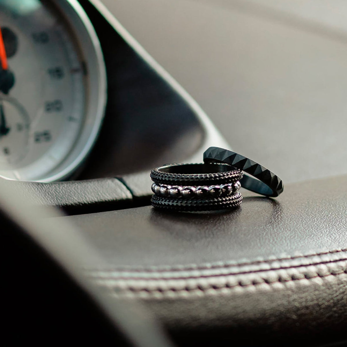 AN JEWELS JEWELRY Mod. AR.R2NS02BK-8 rings displayed on car dashboard, showcasing elegant black and silver design.