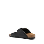 Birkenstock Double-strap leather sandals with black leather, gold-tone buckles, perforated detailing, and a flat rubber sole.