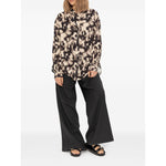 Woman wearing patterned blouse and wide-leg pants with Birkenstock Sandals with buckle strap, standing against a white background.