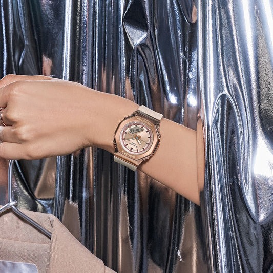CASIO G-SHOCK WATCHES Mod. GM-S2110PG-4AER displayed on a wrist against a metallic background.