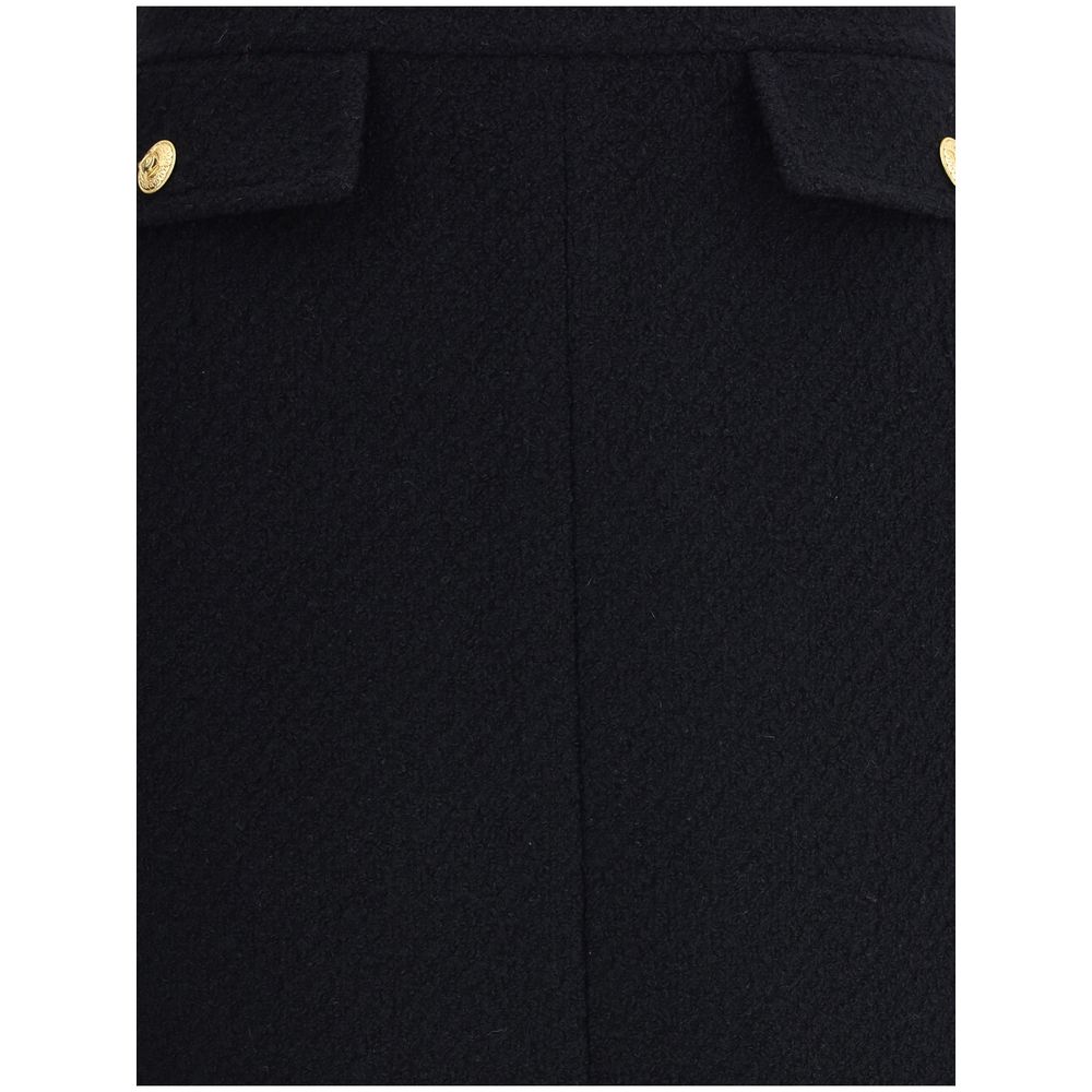 Close-up of Chloé Black Wool Midi Skirt with gold-tone button accents and front flap pockets, highlighting its sleek bouclé design for AW25.