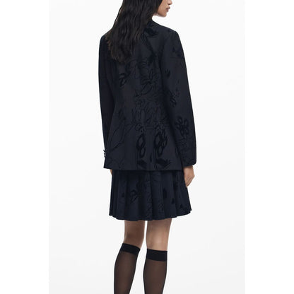 Woman wearing Desigual Black Polyester Women Jacket with floral pattern, featuring V-neck, sleek pockets, and stylish buttons.