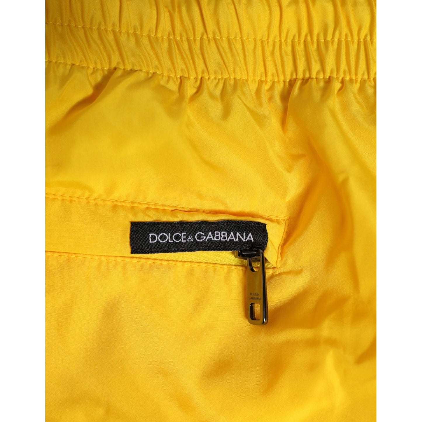 Close-up of Dolce & Gabbana Yellow Drawstring Beachwear Men Shorts Swimwear with logo zip detail.
