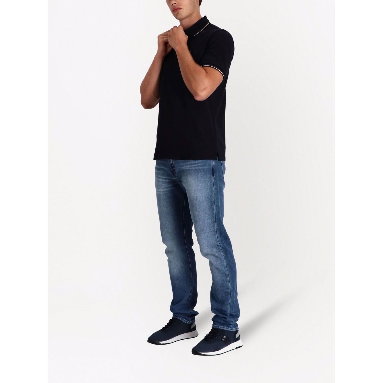 Man wearing Emporio Armani T-shirts and Polos Blue with navy blue polo, jeans, and sneakers.