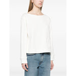 Woman wearing white Emporio Armani logo embroidered sweatshirt with ribbed cuffs, hem, and light blue jeans.