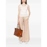 Model wearing Fabiana Filippi Trousers Powder, beige wide-leg, elasticated waist, with side pockets, styled with a white tank and brown bag.