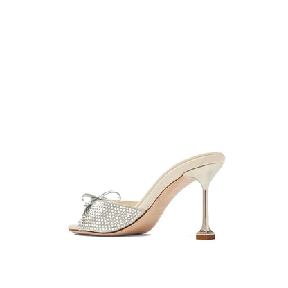 Miu Miu Silver Silk Mules with crystal embellishment, open toe, and bow detail. High heel slip-on design made in Italy for women.