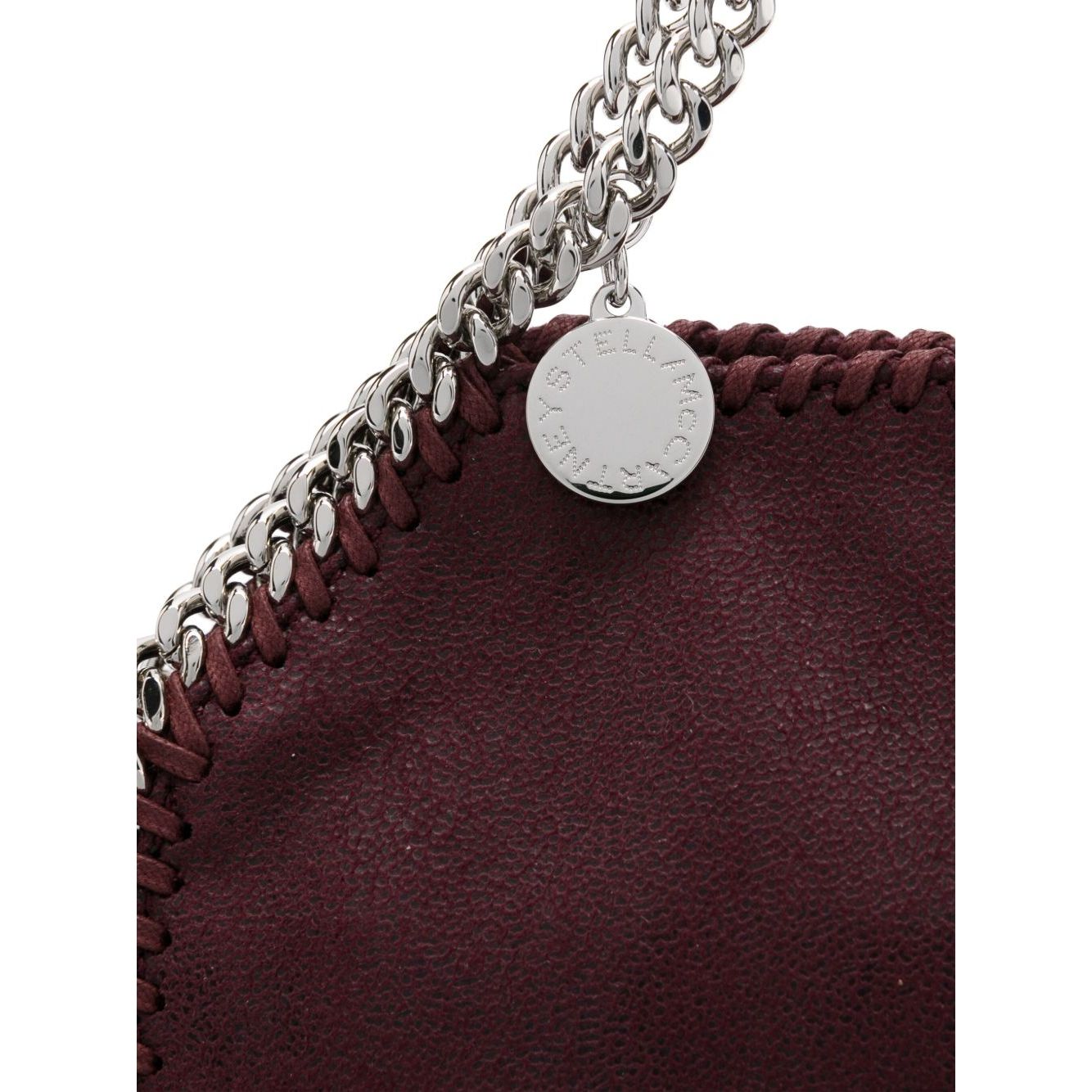 Close-up of Stella McCartney Falabella Tiny crossboydy bag in bordeaux red with chain-link handles and logo charm.