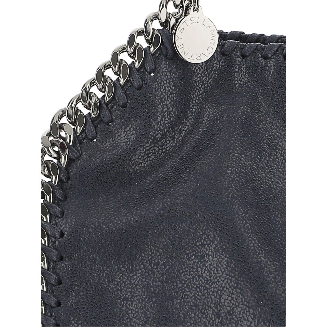 Close-up of chain-link trim on Stella McCartney Falabella mini handbag in blue black with designer tag visible.