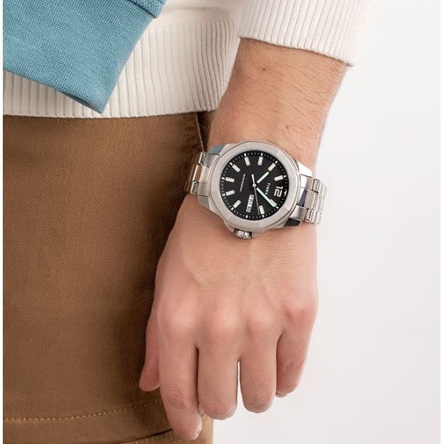 Gent's wrist with TIMEX Mod. ESSEX AVENUE watch, stainless steel bracelet, showing day and date on black dial.