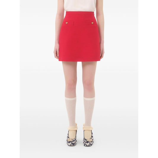 Model wearing a red Valentino Crepe Couture Skirt with heart motif details and concealed side zip, crafted in wool and silk.