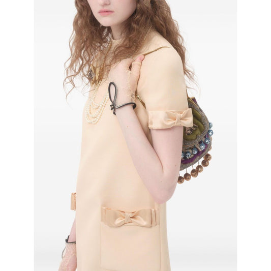 Model wearing Valentino Short Crepe Couture Dress in beige, showcasing rear zip fastening and bow detail, wool and silk blend.