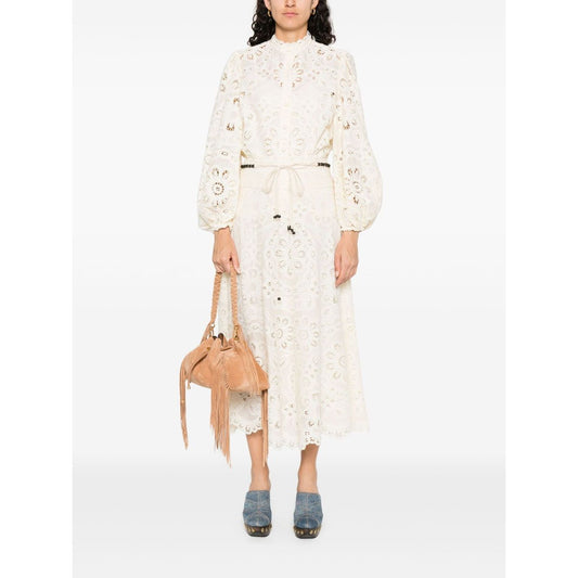 Woman wearing Zimmermann Shirts Ivory blouse with floral detailing, long sleeves, and elasticated cuffs, holding a brown fringe bag.
